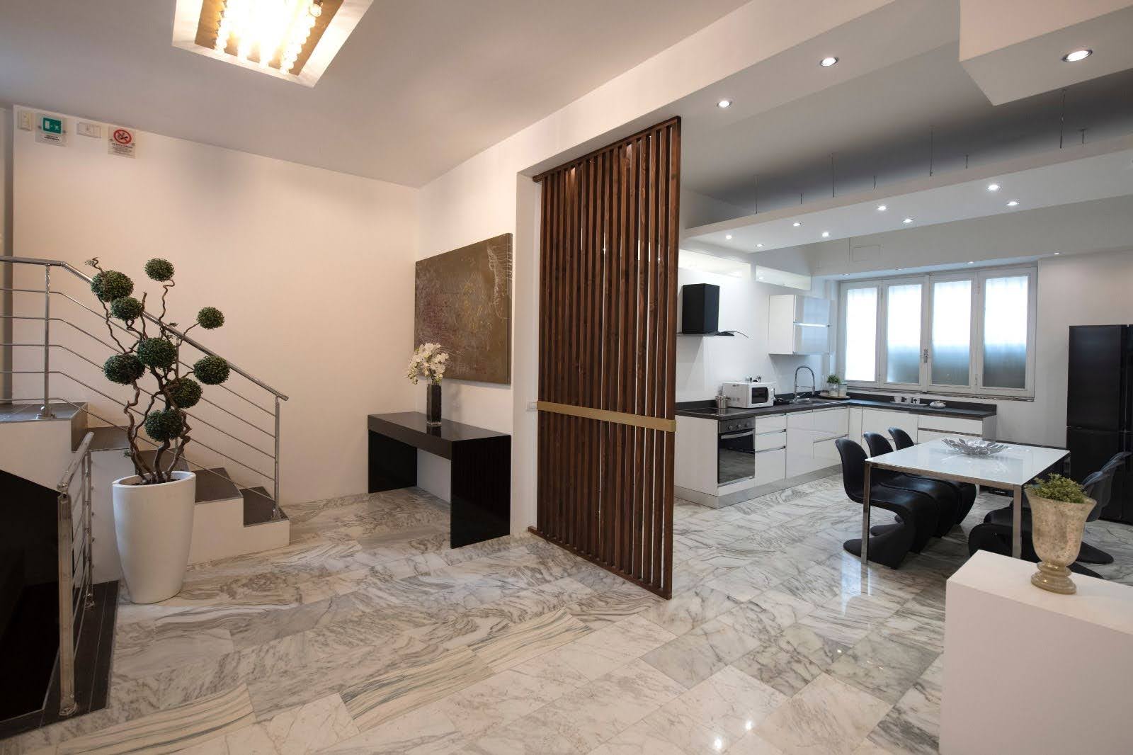 Open-plan kitchen, dining and entrance view with marble flooring and wood divider