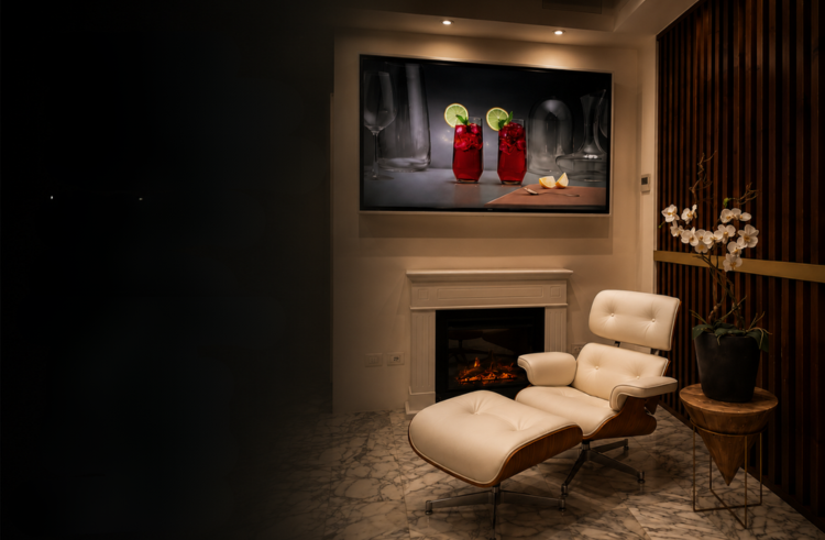 White Eames lounge chair beside the fireplace, walnut screens and marble floor under warm evening light at La Galleria Milano
